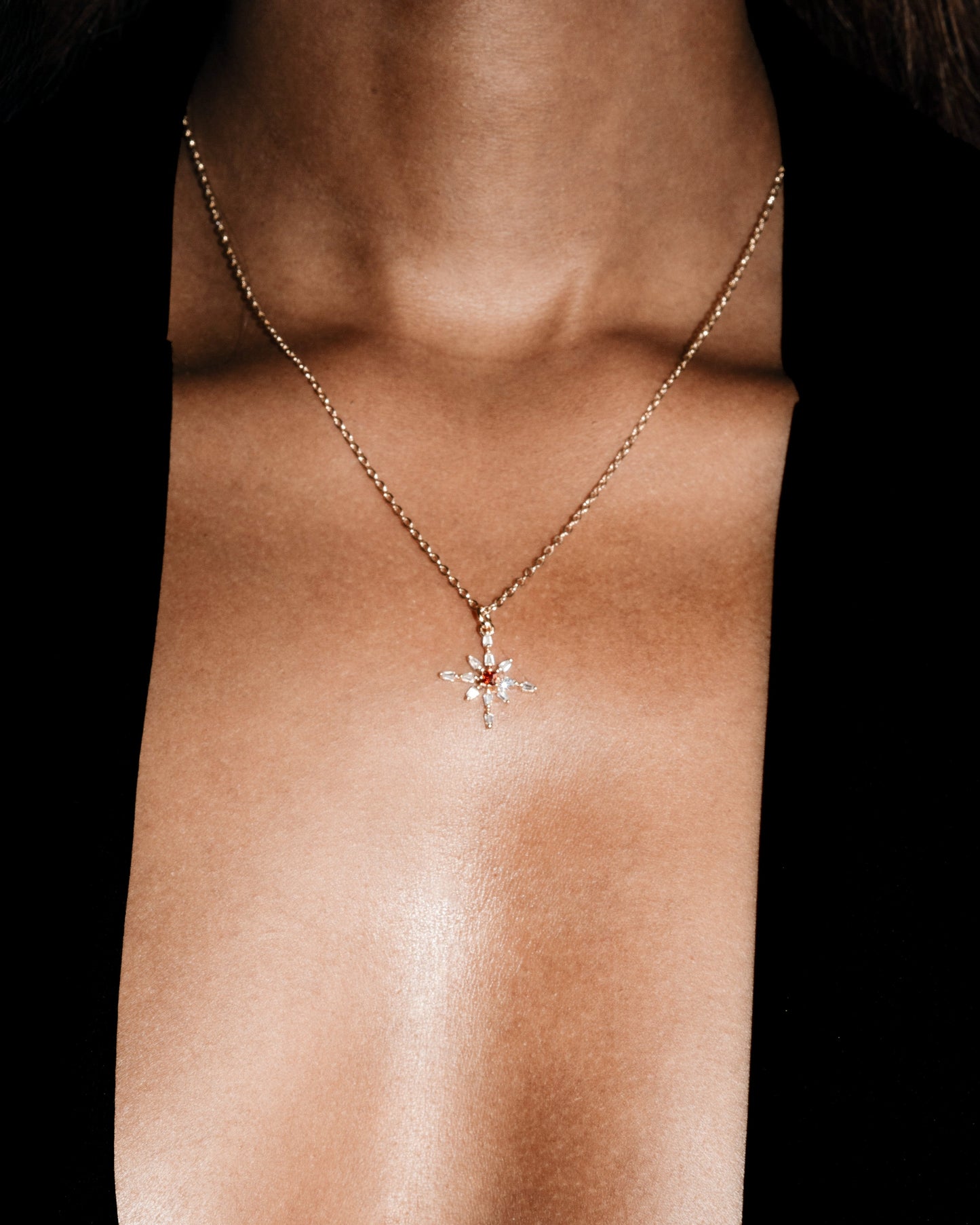Necklace with a floral pendant on a person's neck against a black background