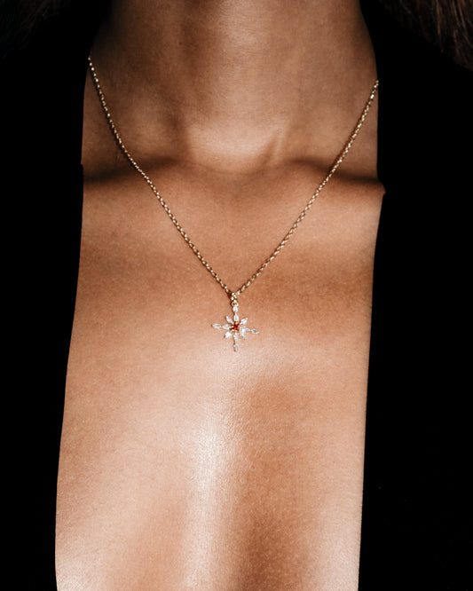 Necklace with a floral pendant on a person's neck against a black background