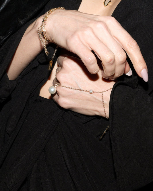 Person wearing a black outfit with jewelry, sitting in a car.