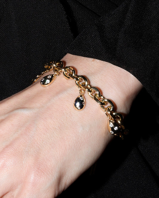 Close-up of a hand wearing a gold bracelet and ring with a black background