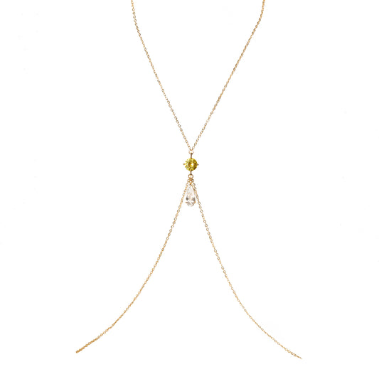 Gold body chain with a yellow and a clear crystal charm on a white background