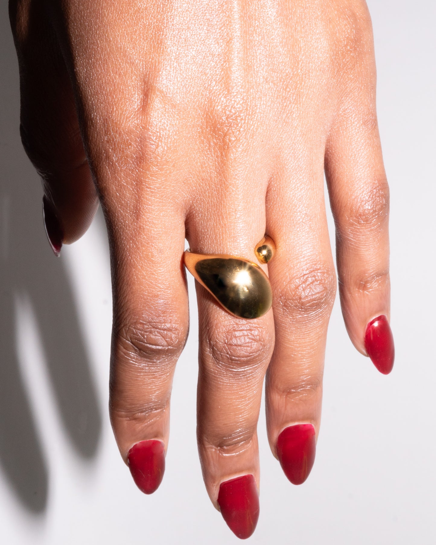 Close-up of hand wearing the Noor Ring – a bold, sculptural 24k gold-plated statement ring from the Knot & Current collection
