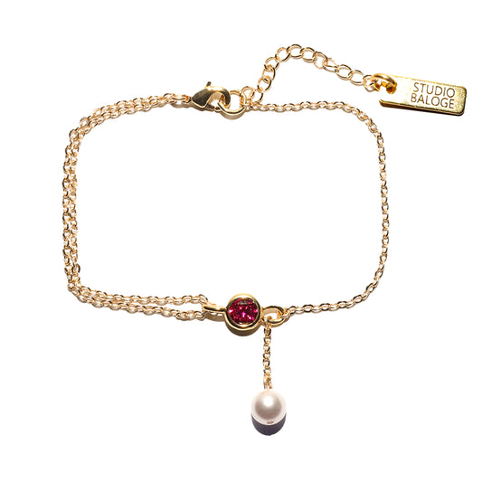 Gold bracelet with a pink gemstone and pearl on a white background, featuring the Studio Baloge brand.