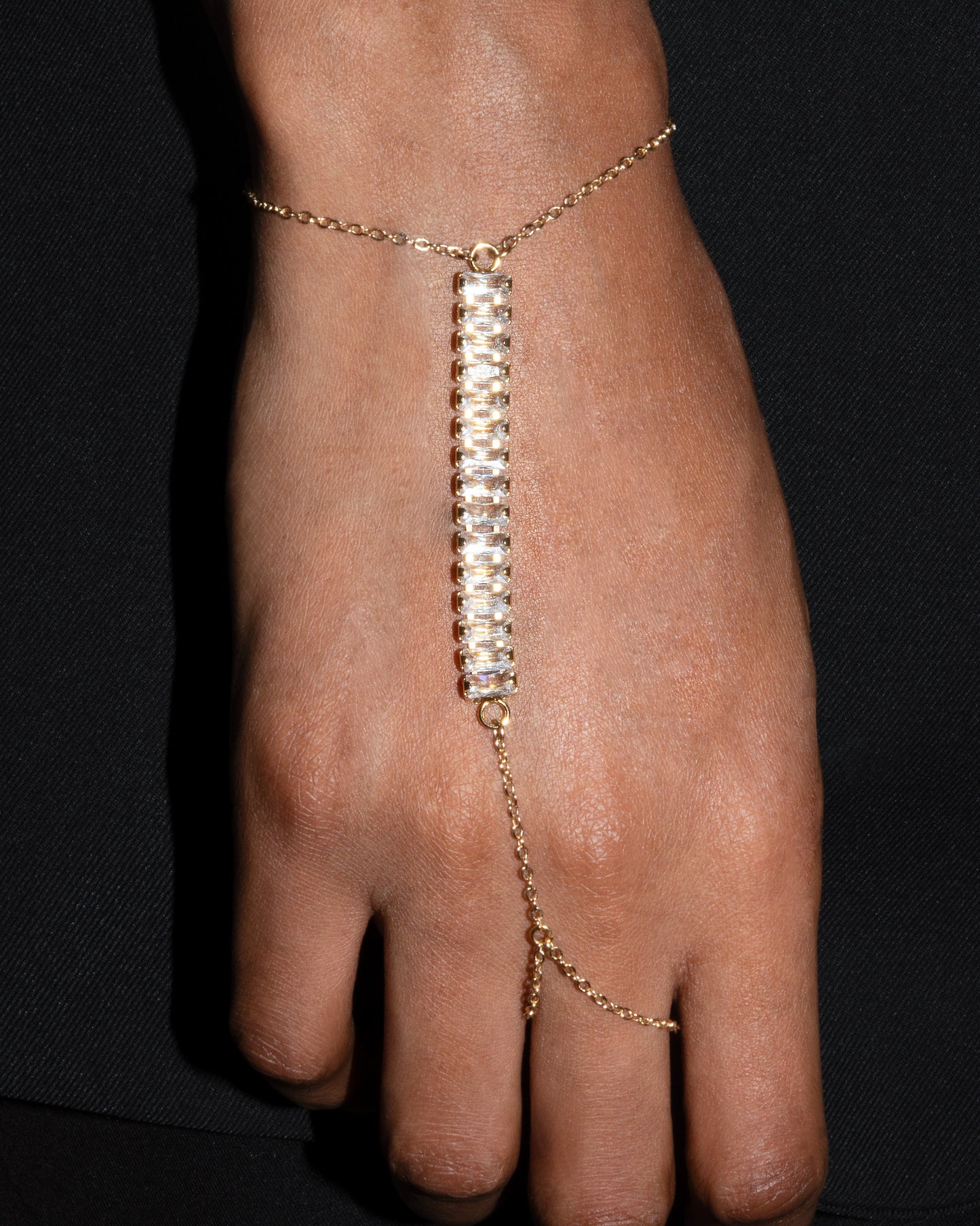 Gesture hand harness by StudioBaloge — crystal bar detail with gold chain connecting wrist to finger.