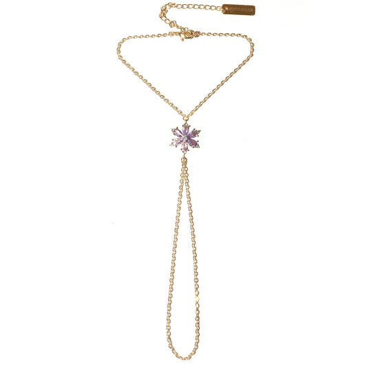 Gold hand chain with a purple flower pendant on a white background