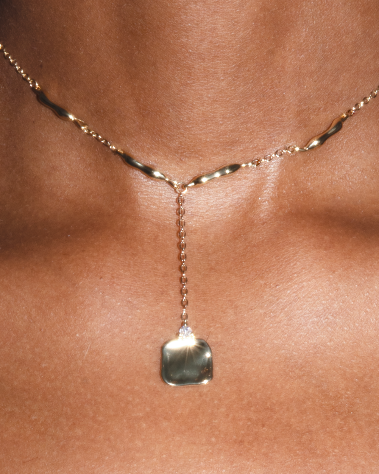Close-up of the Suspendue Necklace – Short by Studio Baloge, showcasing the twisted gold-filled links and a single molten pendant drop resting above the collarbone.