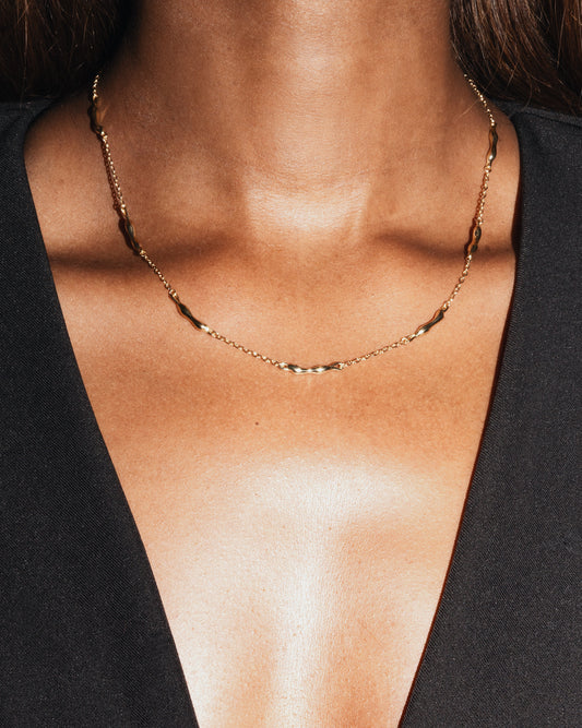 Gold Sculptural necklace on model neckline wearing black blazer