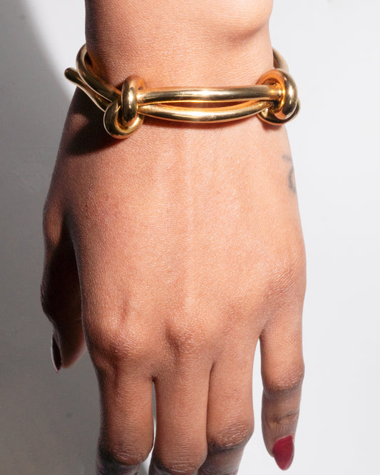 Close-up of a hand wearing the Vanta Knot Bracelet by Studio Baloge—bold 24k gold-plated bracelet with sculptural knot detail.