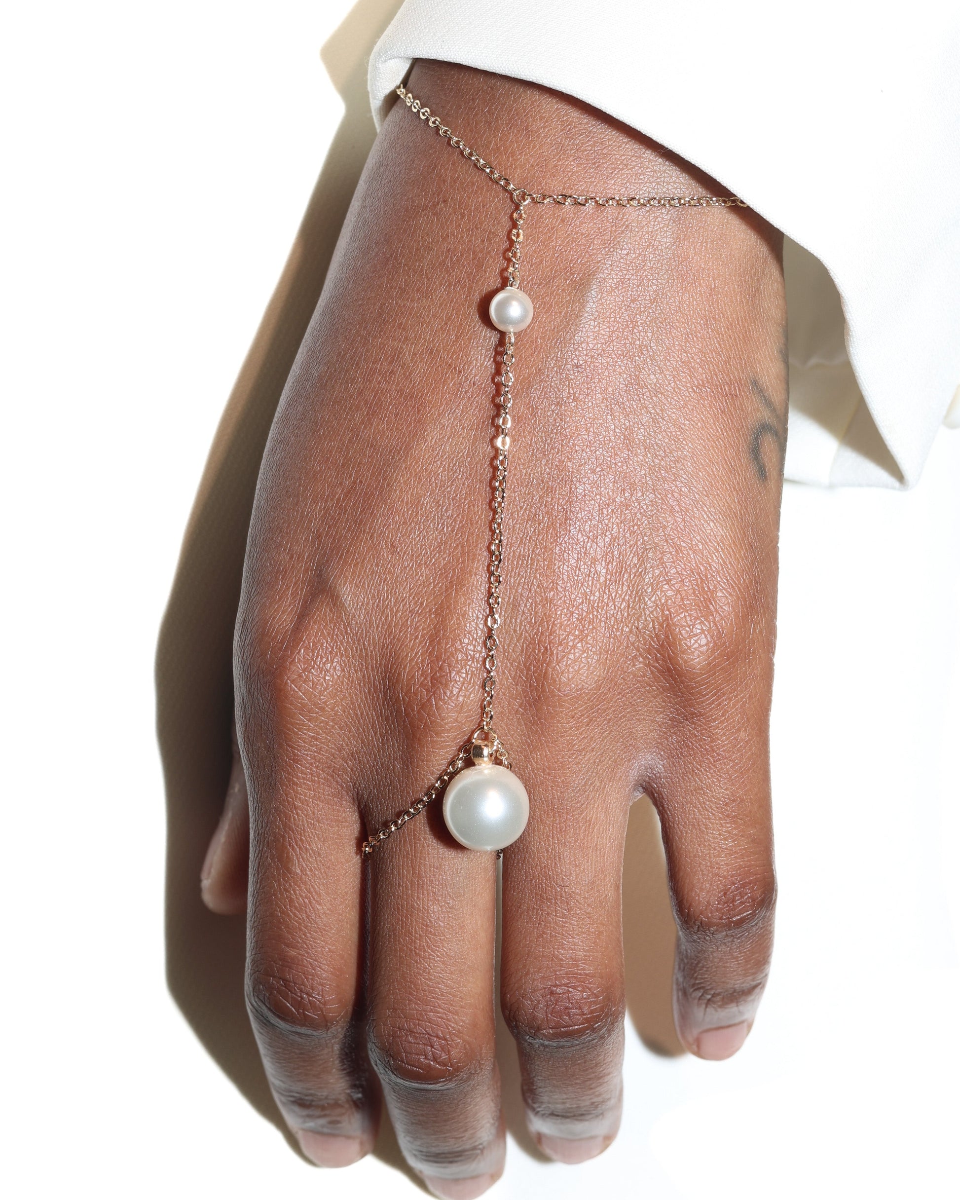 Hand wearing gold chain hand harness with pearl embellishments 