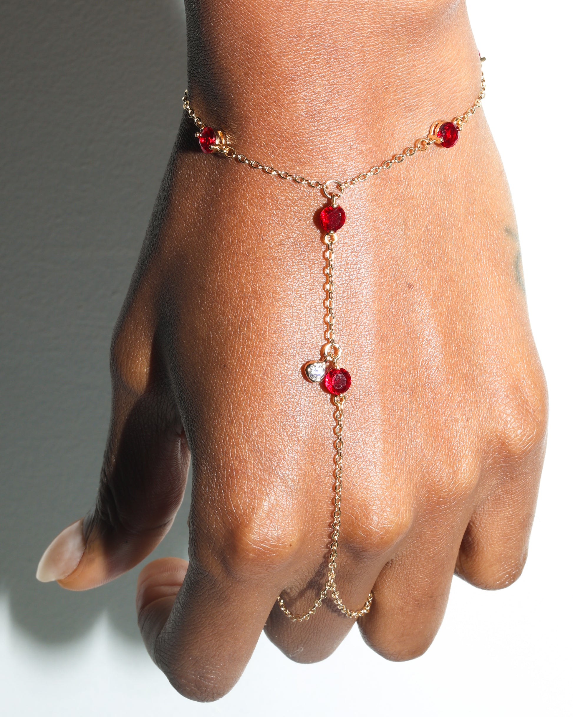 Gold hand harness with red gemstones on a person's hand
