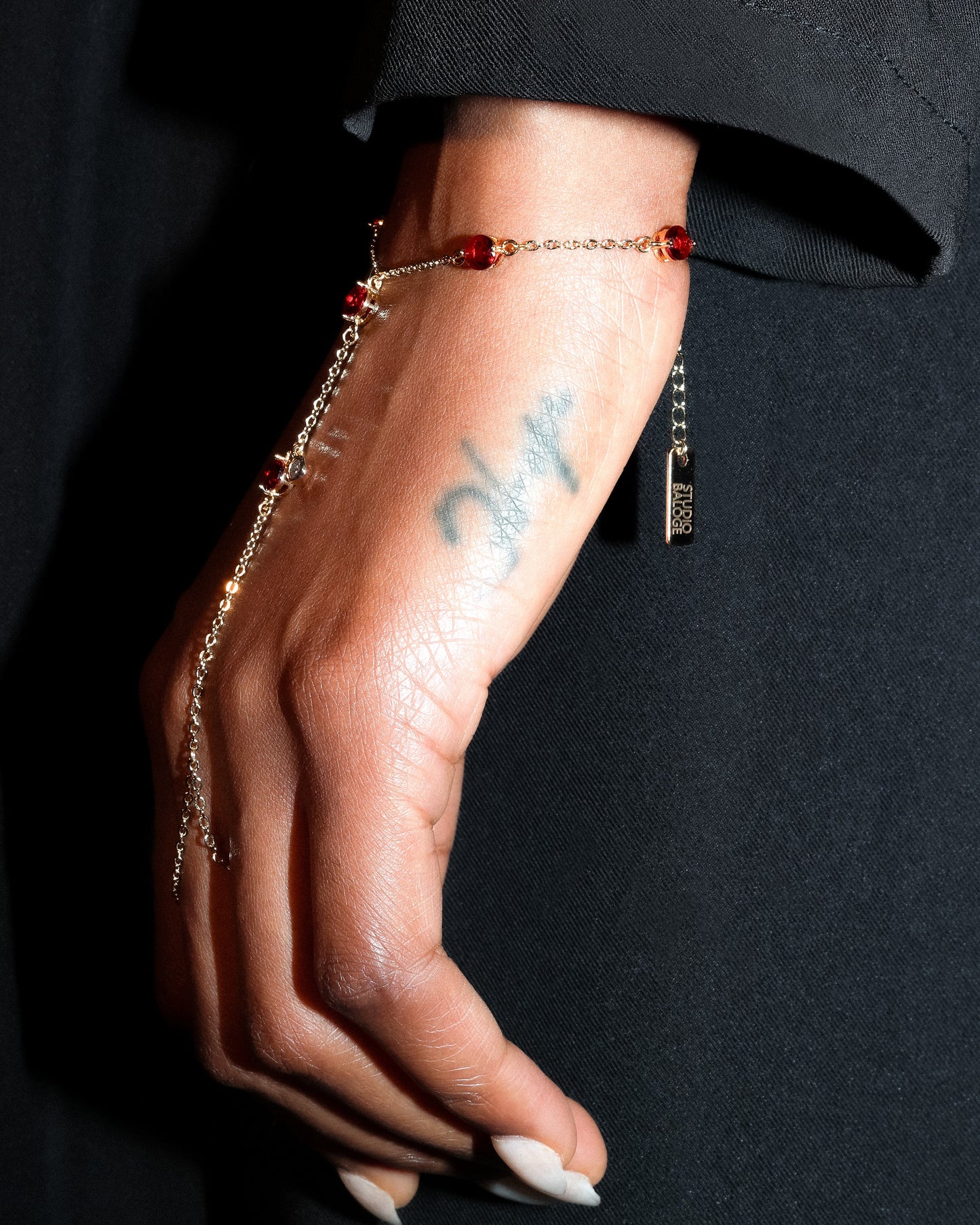 Gold Hand Harness with red gemstones on a person's hand against a black background