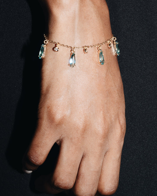 Bracelet with teardrop-shaped gemstones on a wrist against a dark background