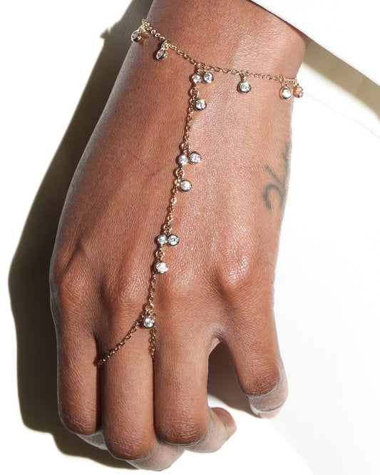 Hand wearing a delicate bracelet on a plain background