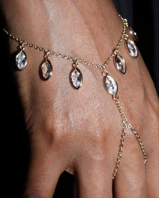 Gold chain bracelet with teardrop-shaped crystals on a wrist against a black background