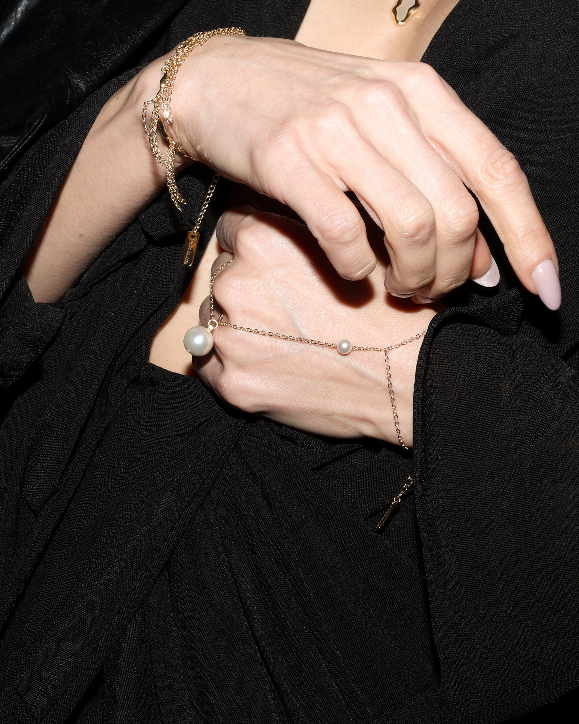 Person wearing a black outfit with jewelry, sitting in a car.