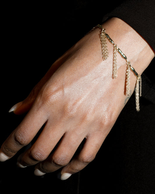 Gold bracelet on a hand against a black background