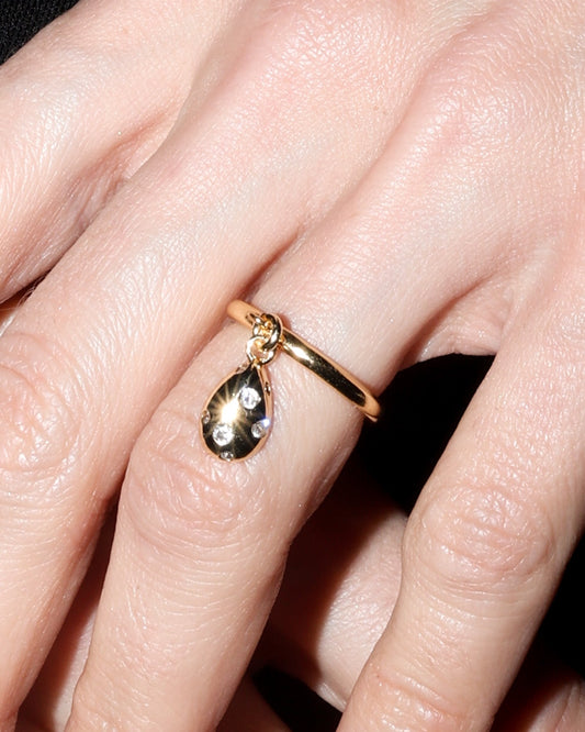 Close-up of a hand wearing a gold ring with a black background