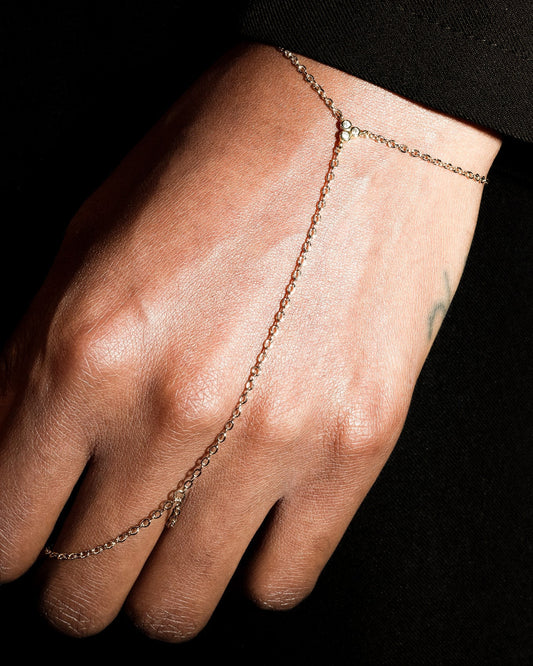 Gold chain bracelet on a wrist against a black background