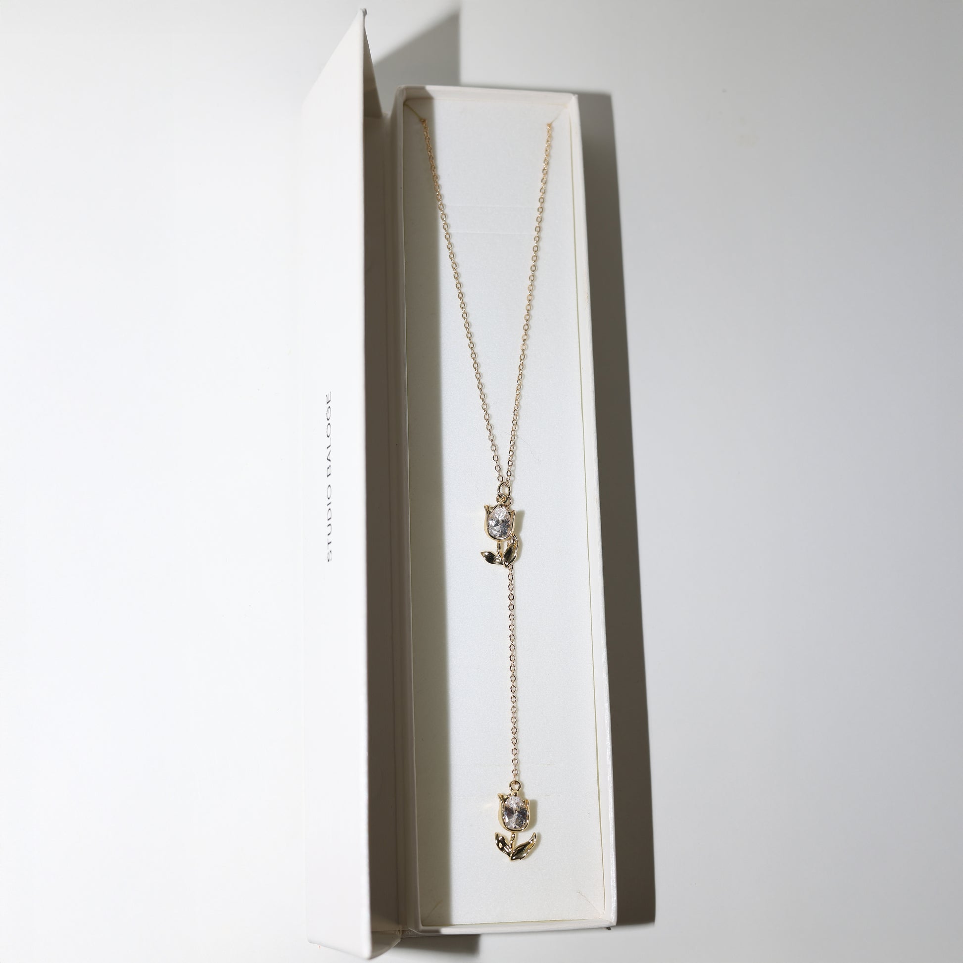 Gold lariat necklace with two tulip pendants in Studio Baloge Box
