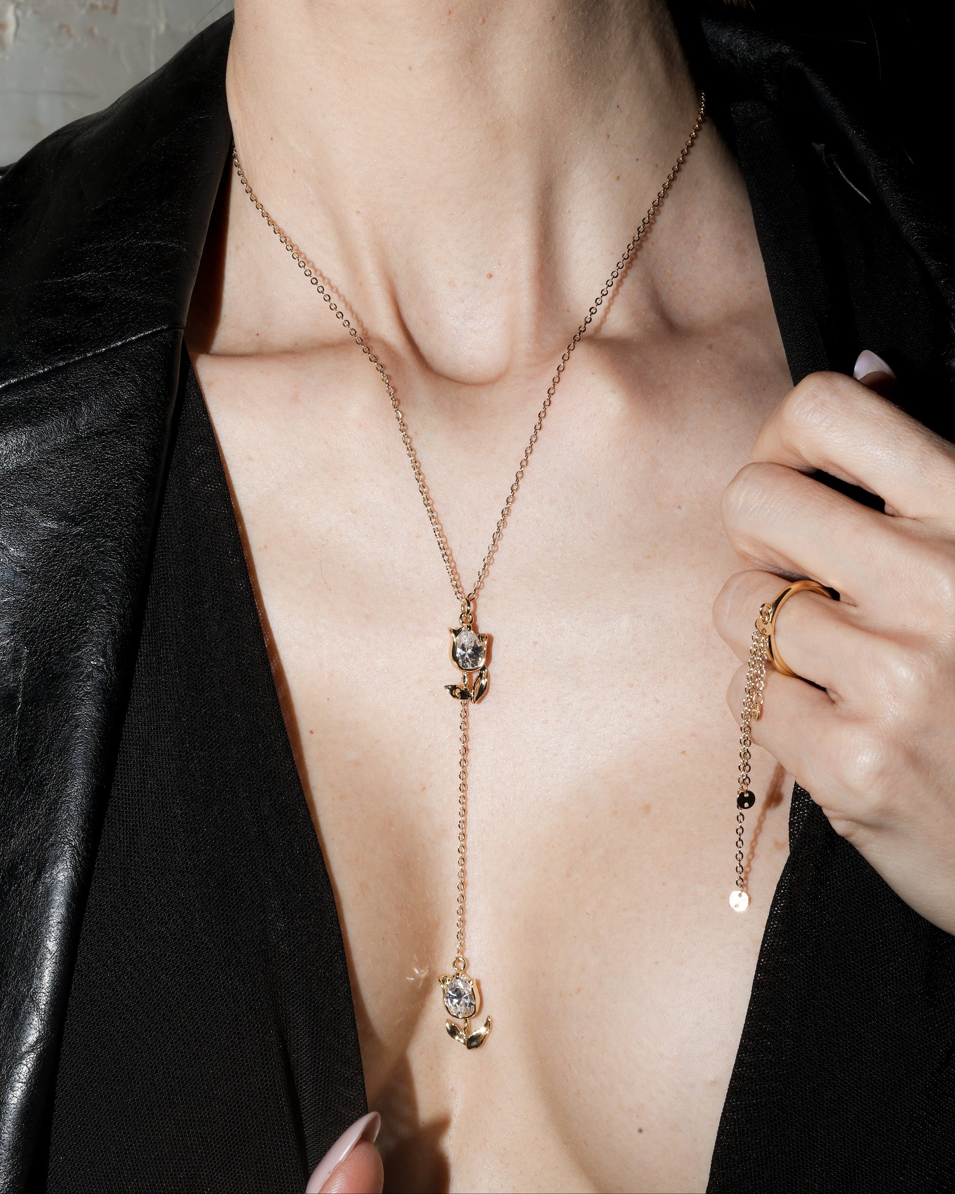 Close-up of a person wearing a gold necklace with a black leather jacket.