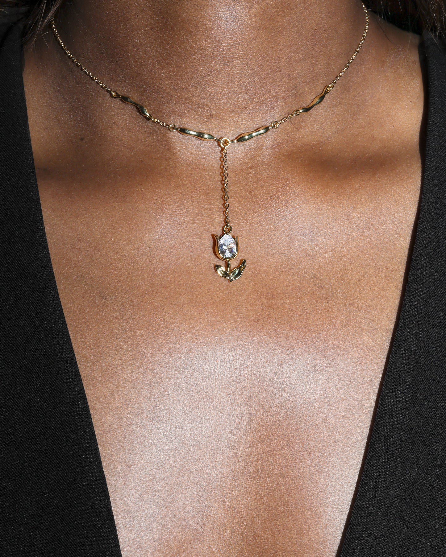 Gold necklace with a pendant on a person wearing a black top