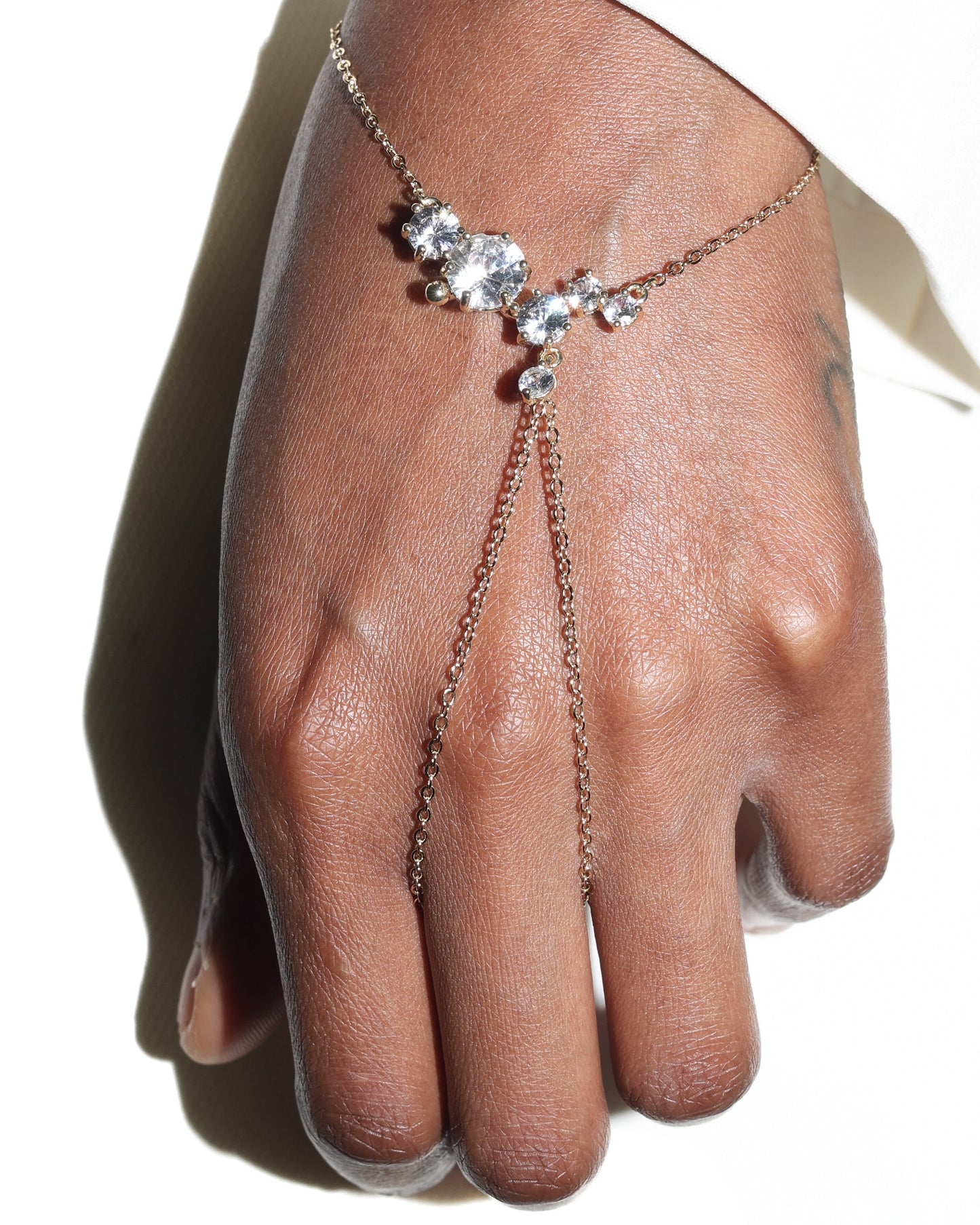 Hand wearing a delicate silver bracelet with small stones on a white background