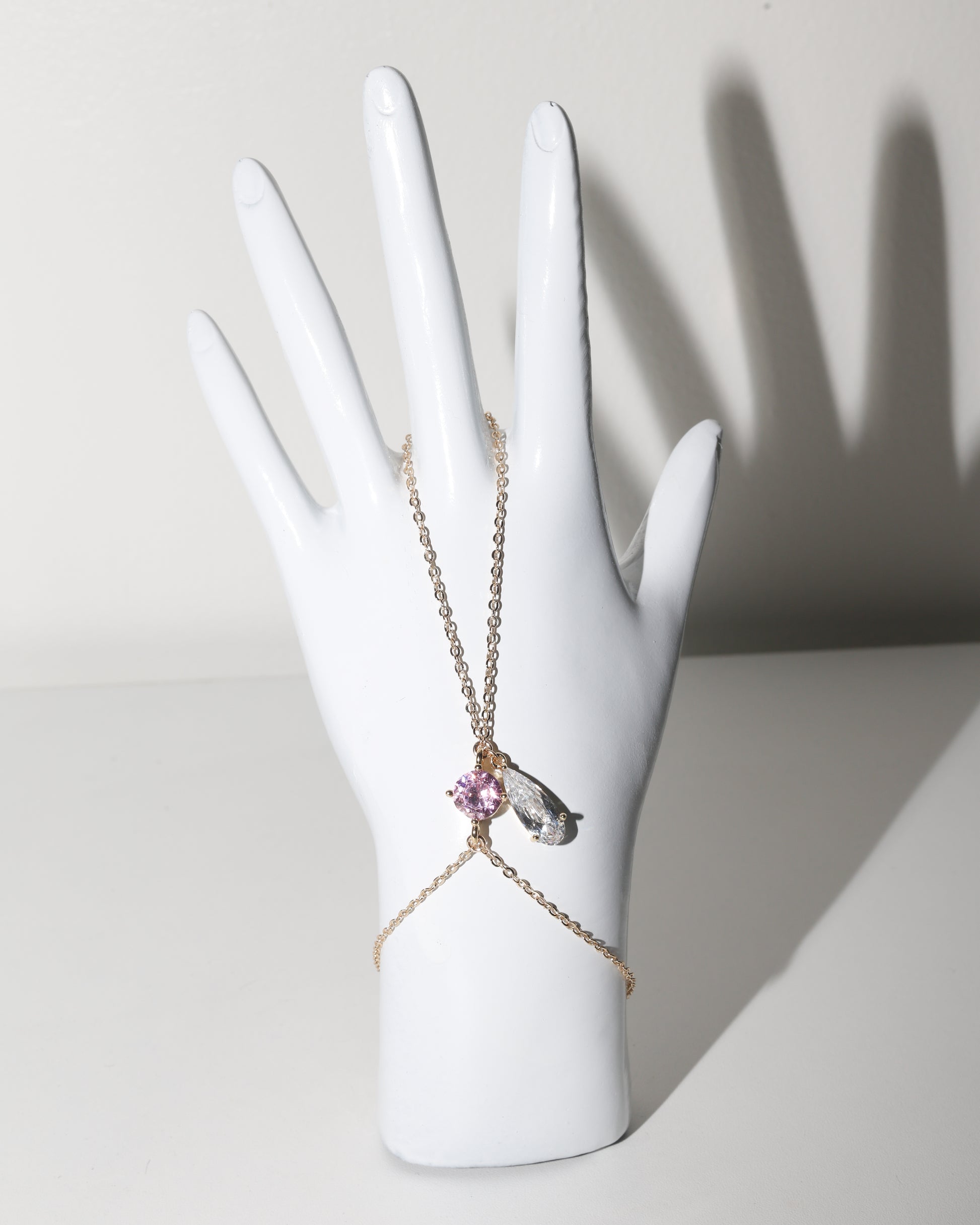 Necklace with a pendant on a white mannequin hand against a neutral background