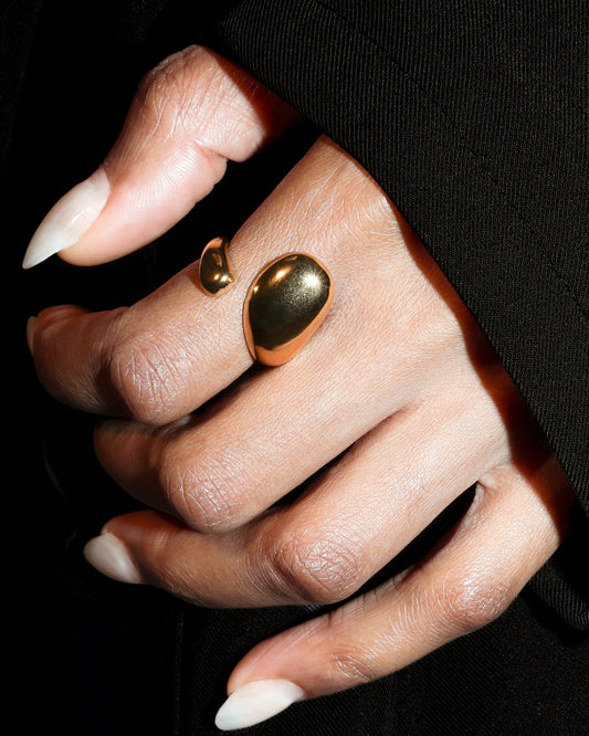 Hand wearing two gold rings with a black background