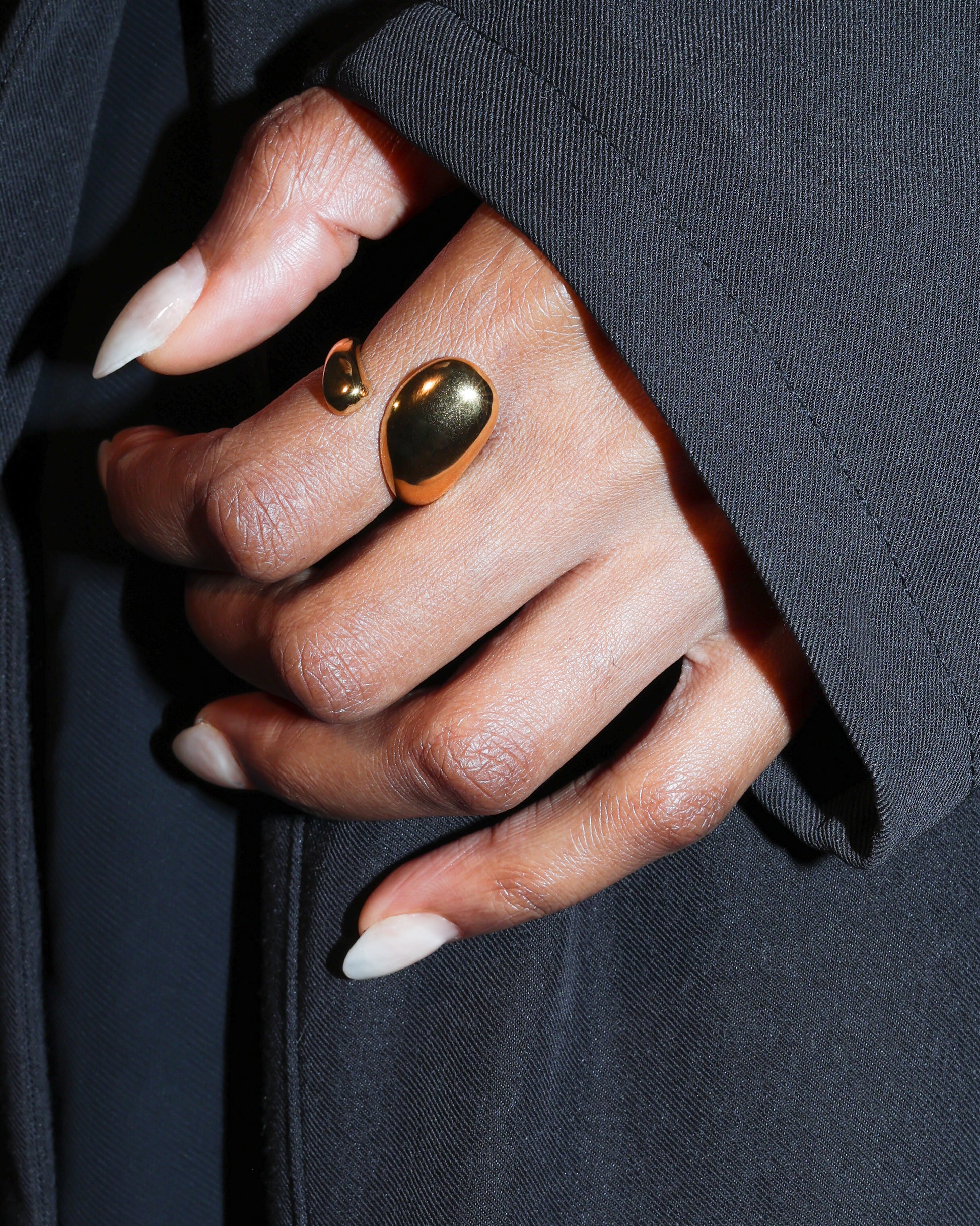 Close-up of a hand wearing a gold rings with a dark background