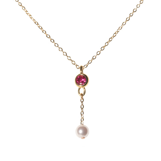 Gold necklace with a pink gemstone and pearl pendant on a white background