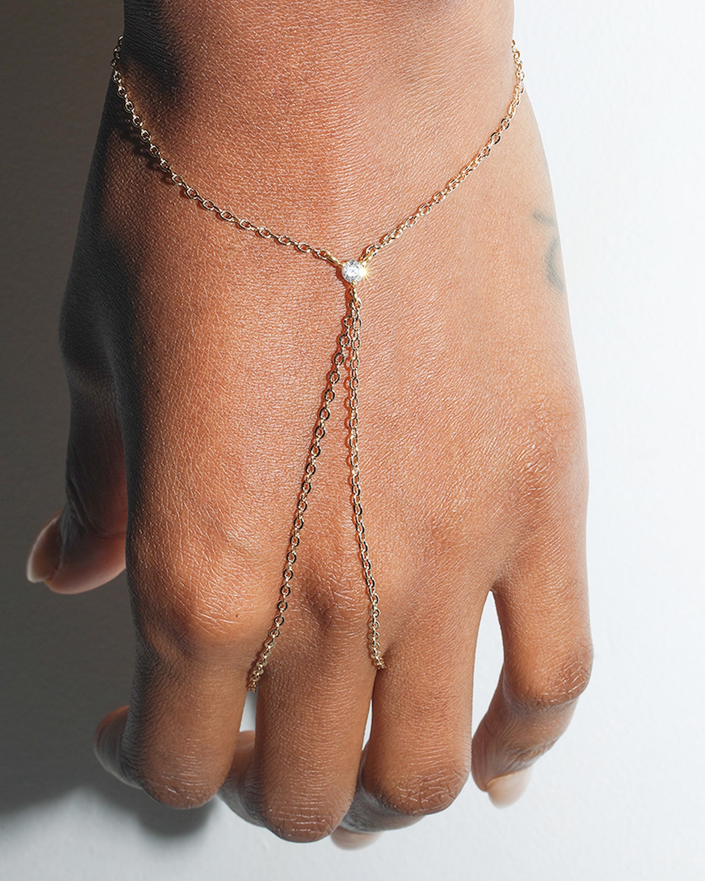 Minimal gold hand harness with crystal detail worn on hand