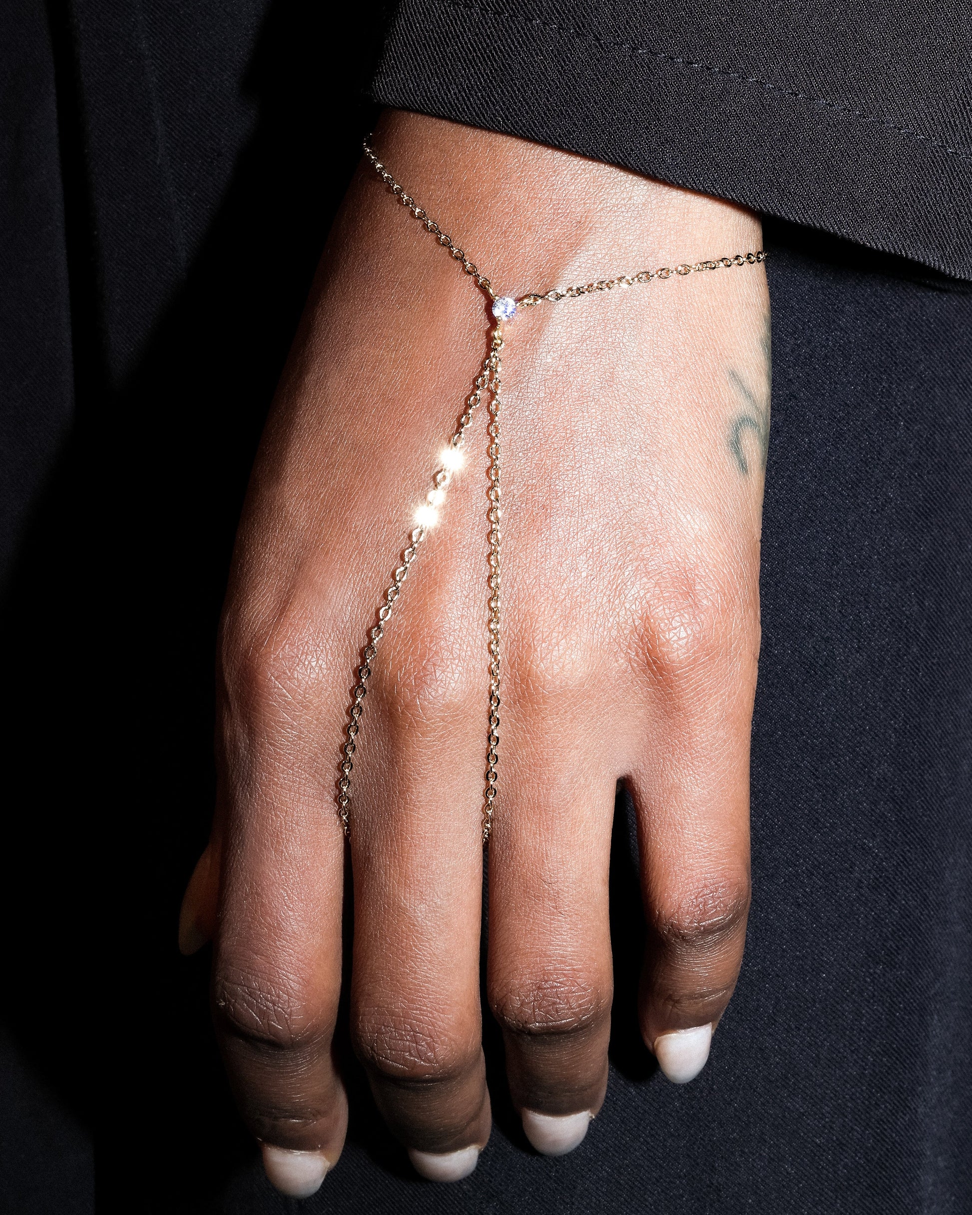 Hand wearing a delicate chain bracelet on a black background