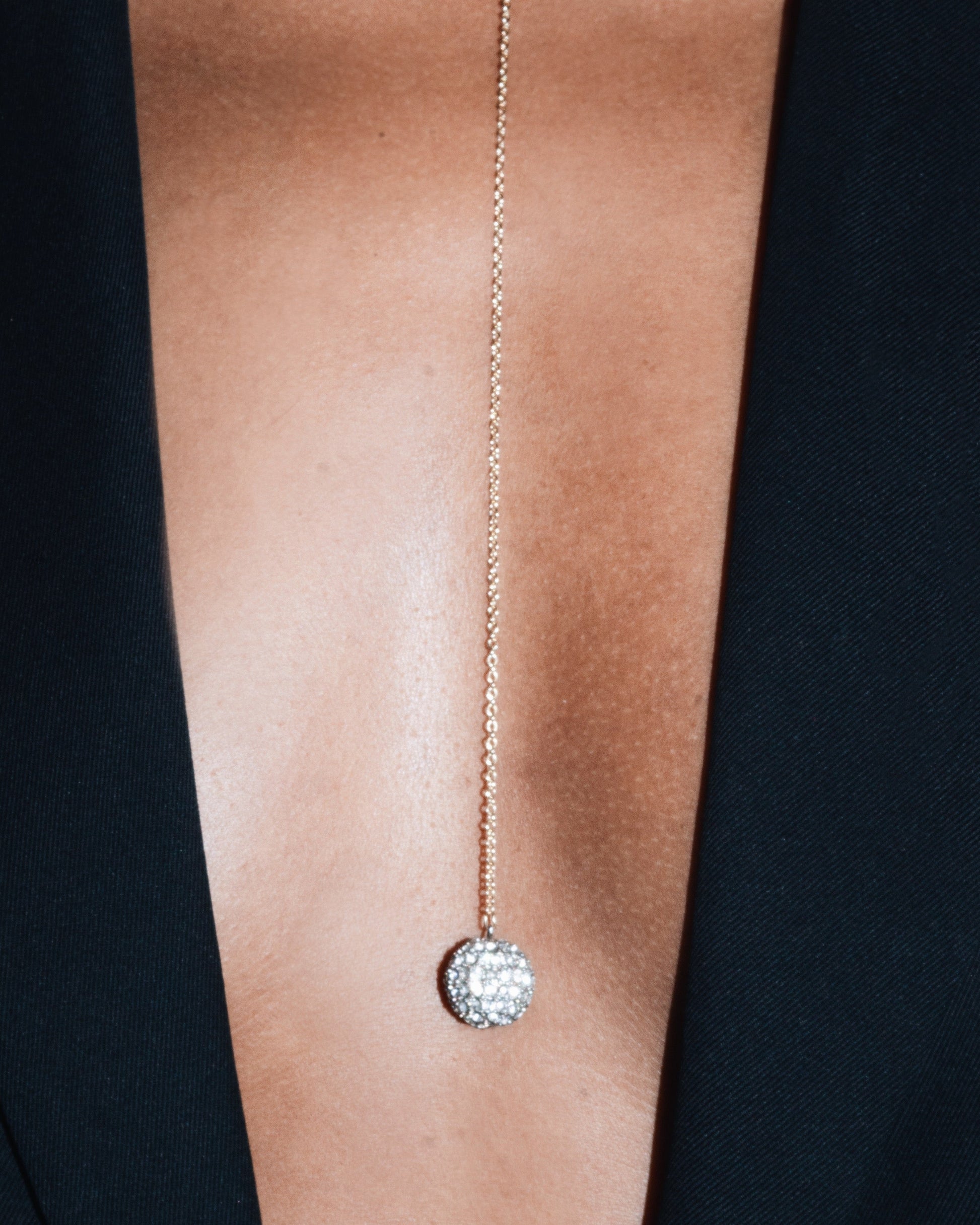 Gold necklace with a pendant on a person wearing a black outfit