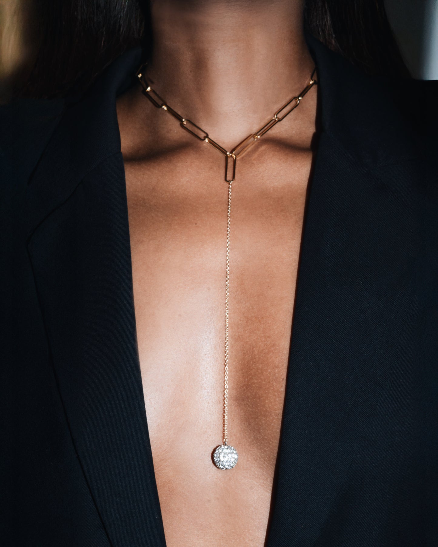 Gold necklace with a pendant on a person wearing a black outfit