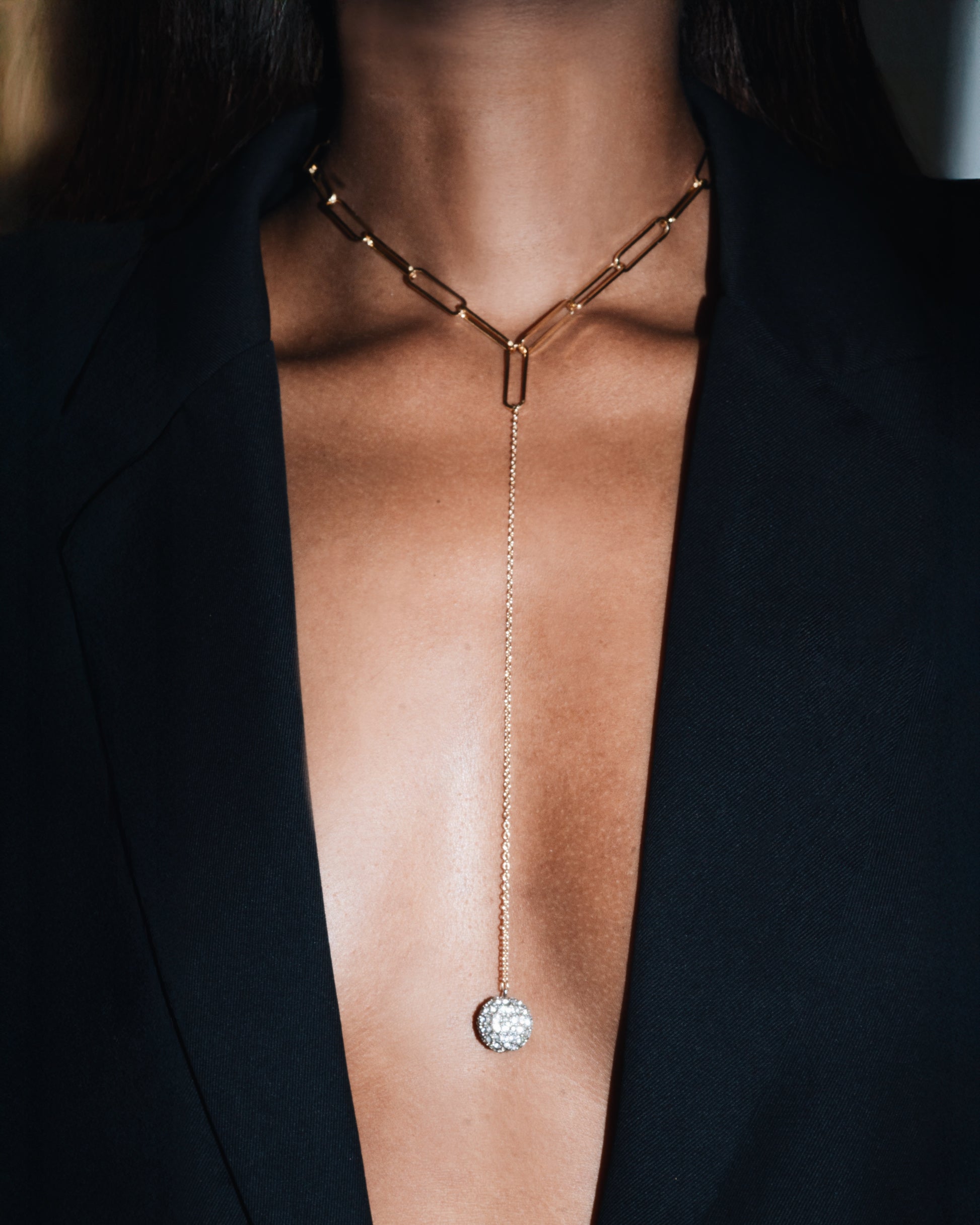 Gold necklace with a pendant on a person wearing a black outfit
