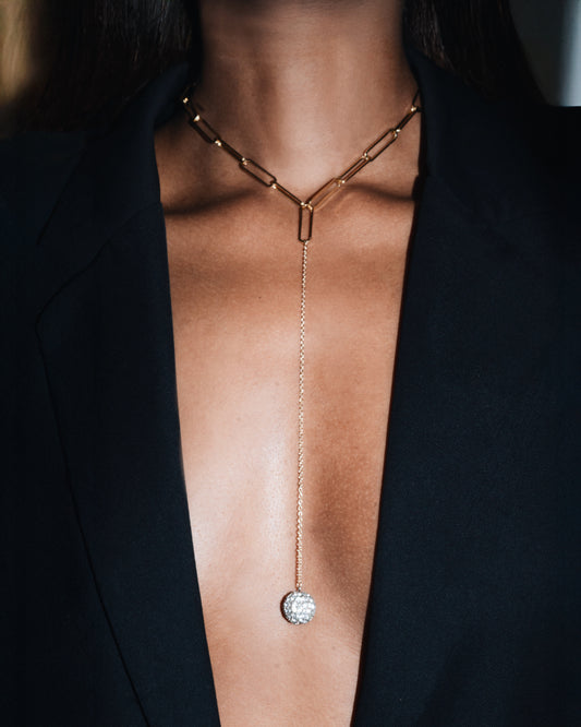 Gold necklace with a pendant on a person wearing a black outfit
