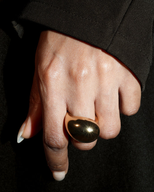 Hand wearing a gold ring on a black background