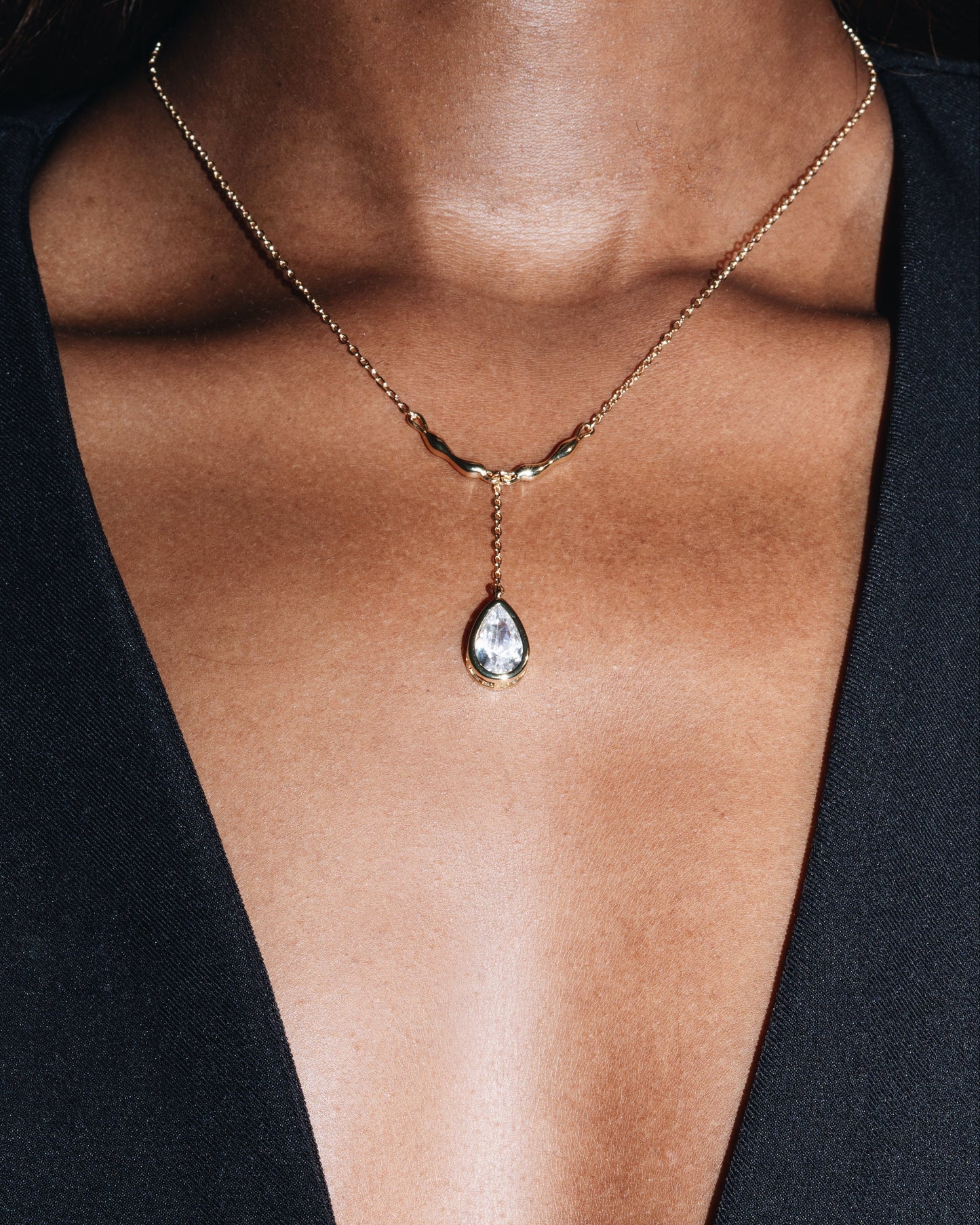 Necklace with a teardrop-shaped pendant on a person wearing a black top.