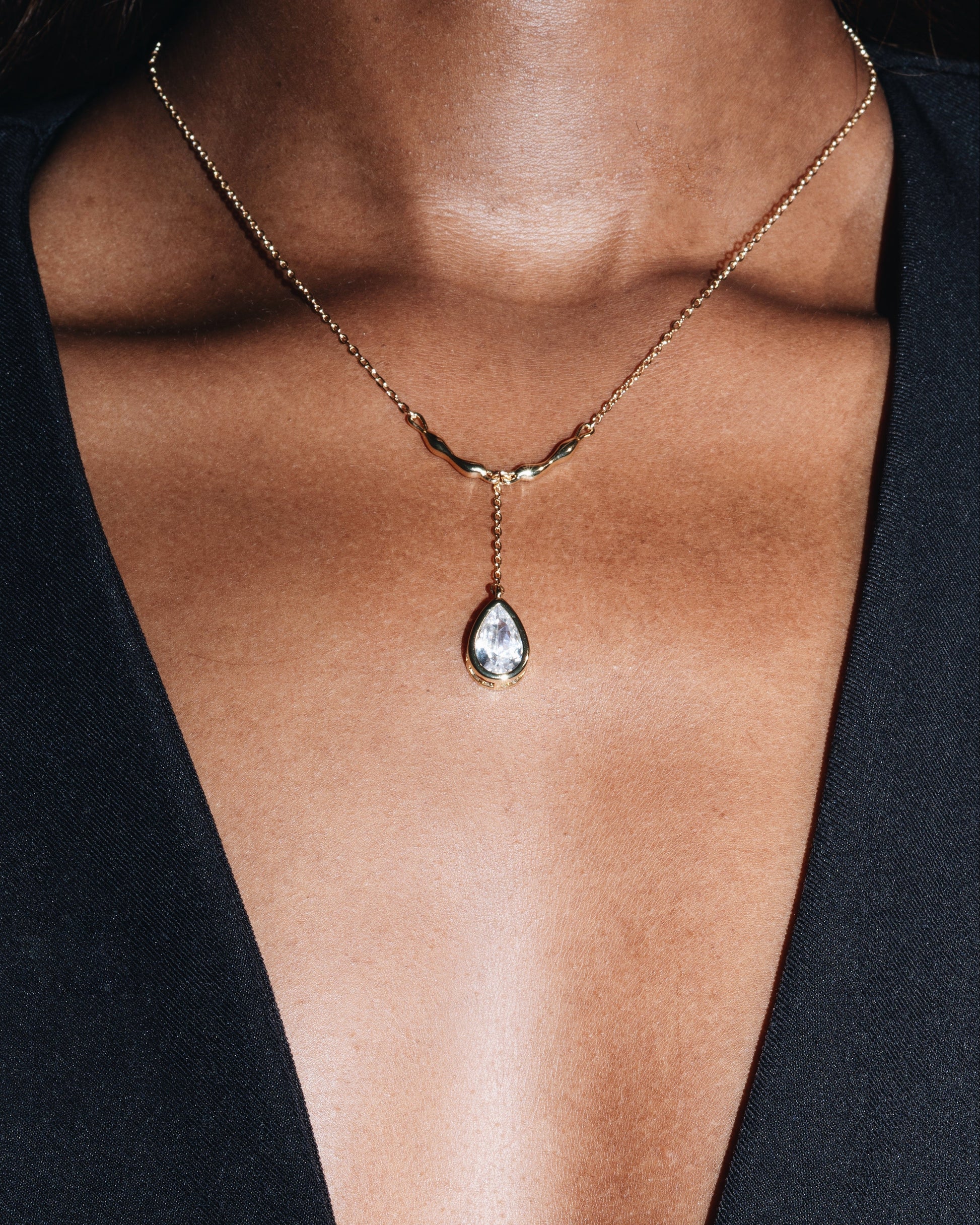 Necklace with a teardrop-shaped pendant on a person wearing a black top.