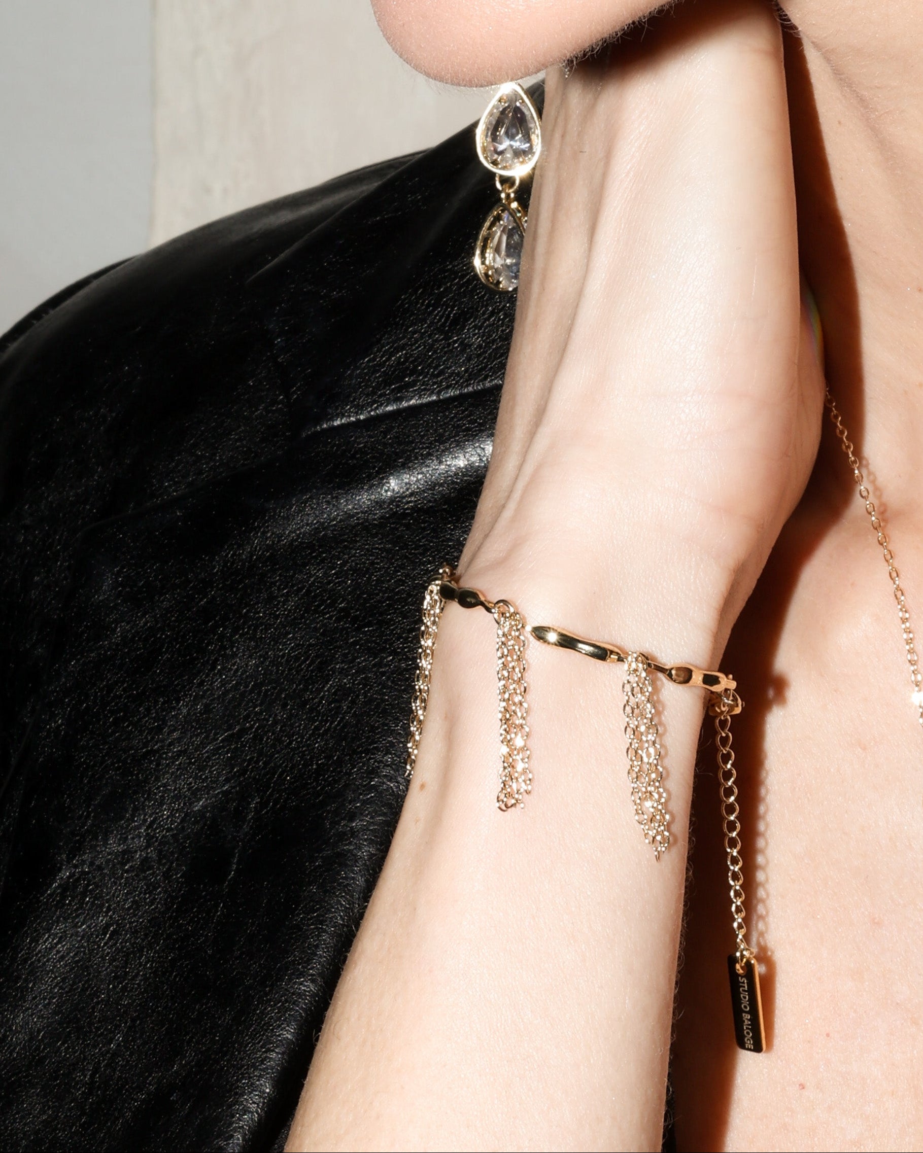 Close-up of a person wearing gold jewelry with dangling earrings and a necklace.