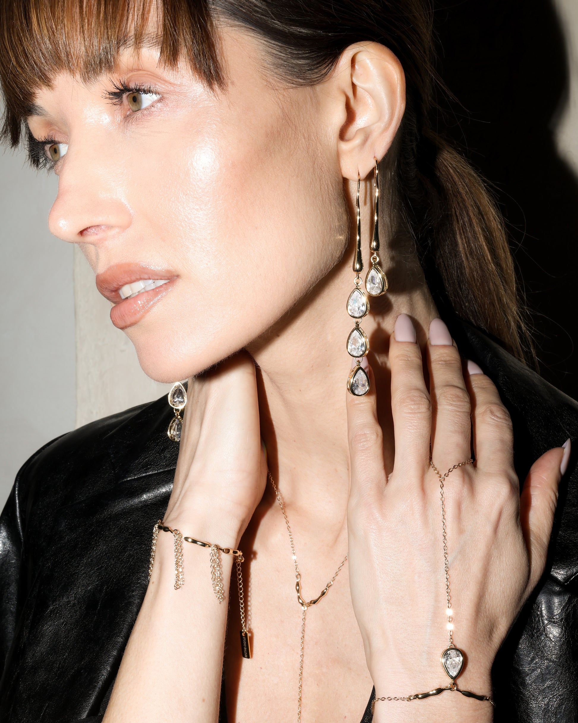 Close-up of a person wearing gold jewelry with dangling earrings and a necklace.