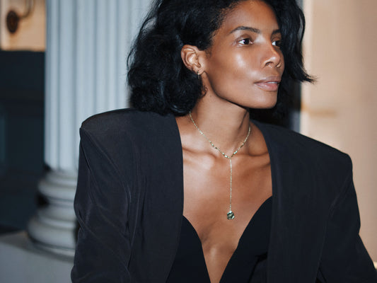 Woman wearing a black blazer with a Drop Necklace from Studio Baloge against a blurred background