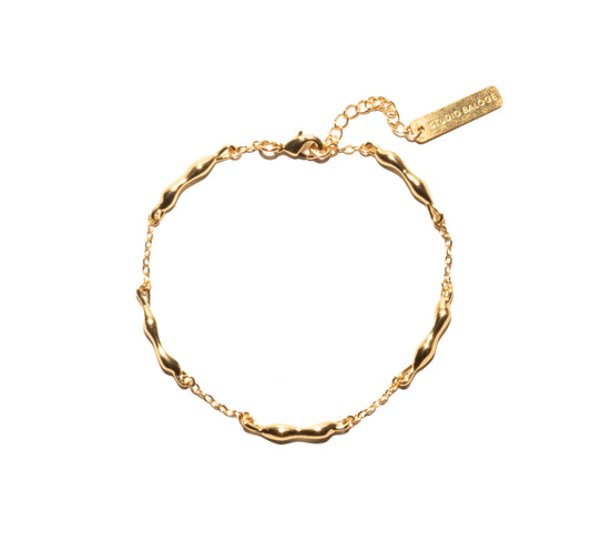 Gold bracelet with a visible brand tag on a white background
