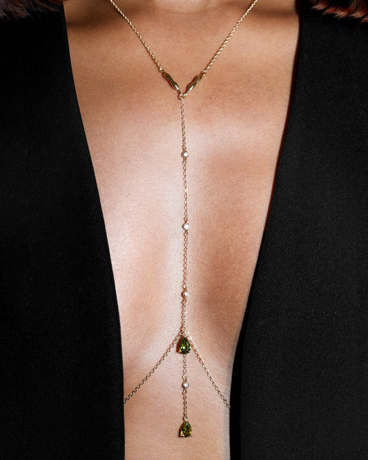 Gold body chain with olive green gemstones on a black background