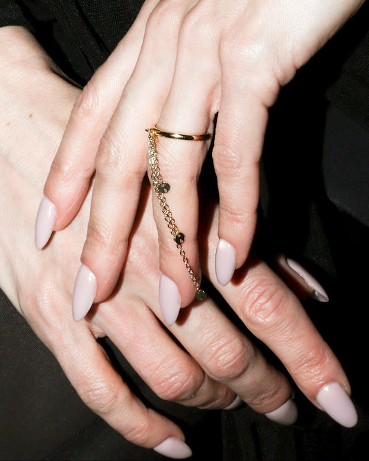 Close-up of a person wearing a black outfit with a focus on hands and jewelry.