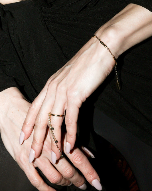 Close-up of a person wearing a black outfit with a focus on hands and jewelry.