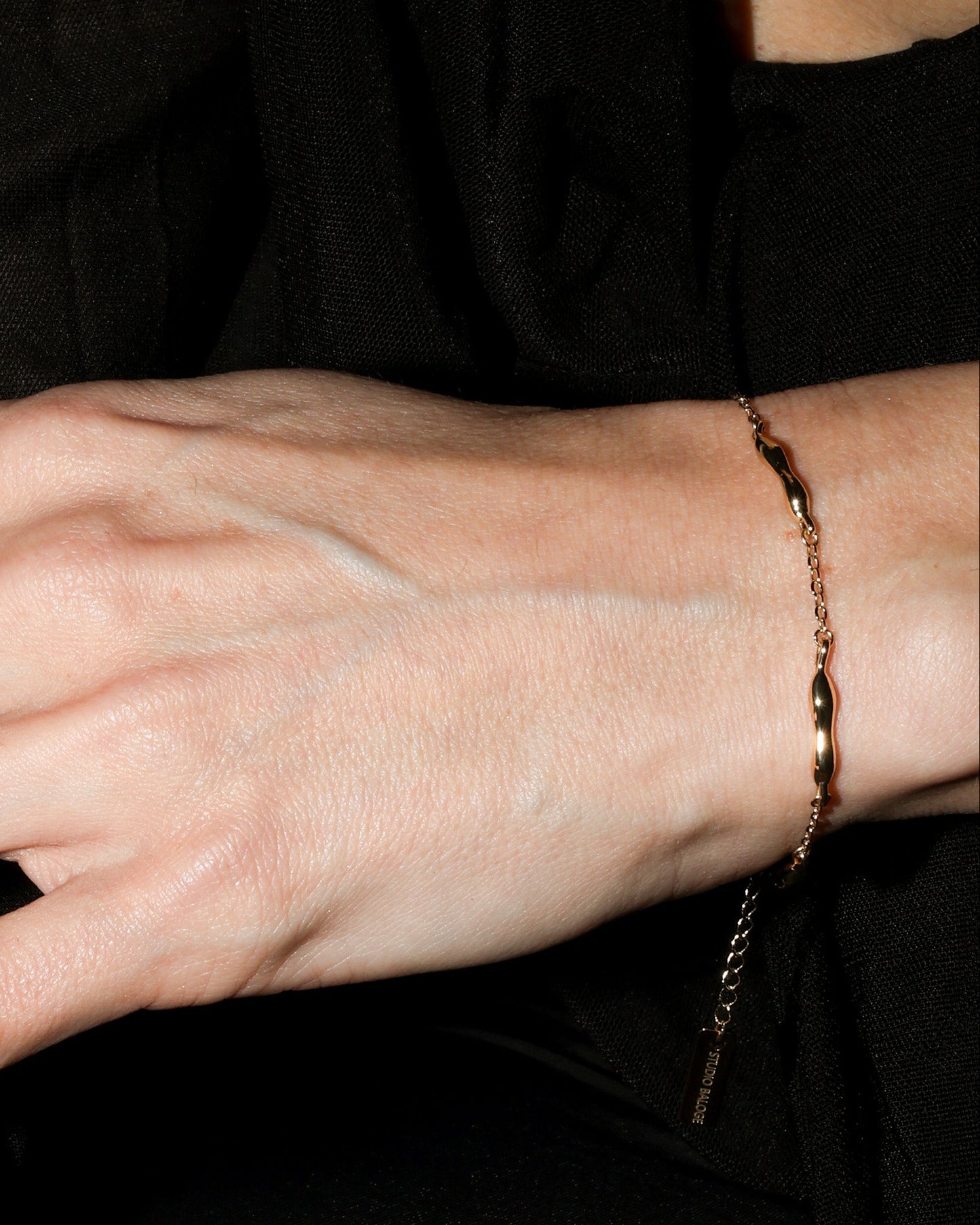 Close up to gold chain bracelet with molten bar.