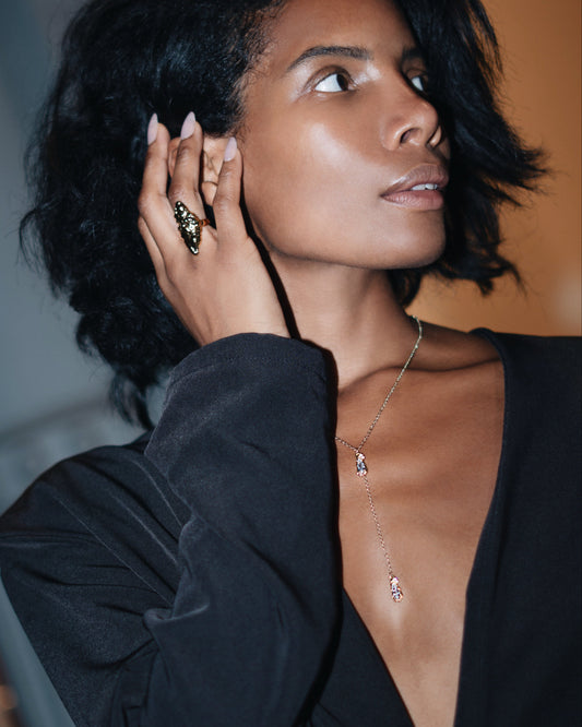 Woman wearing a black top with a plunging neckline, gold necklace, and earrings.